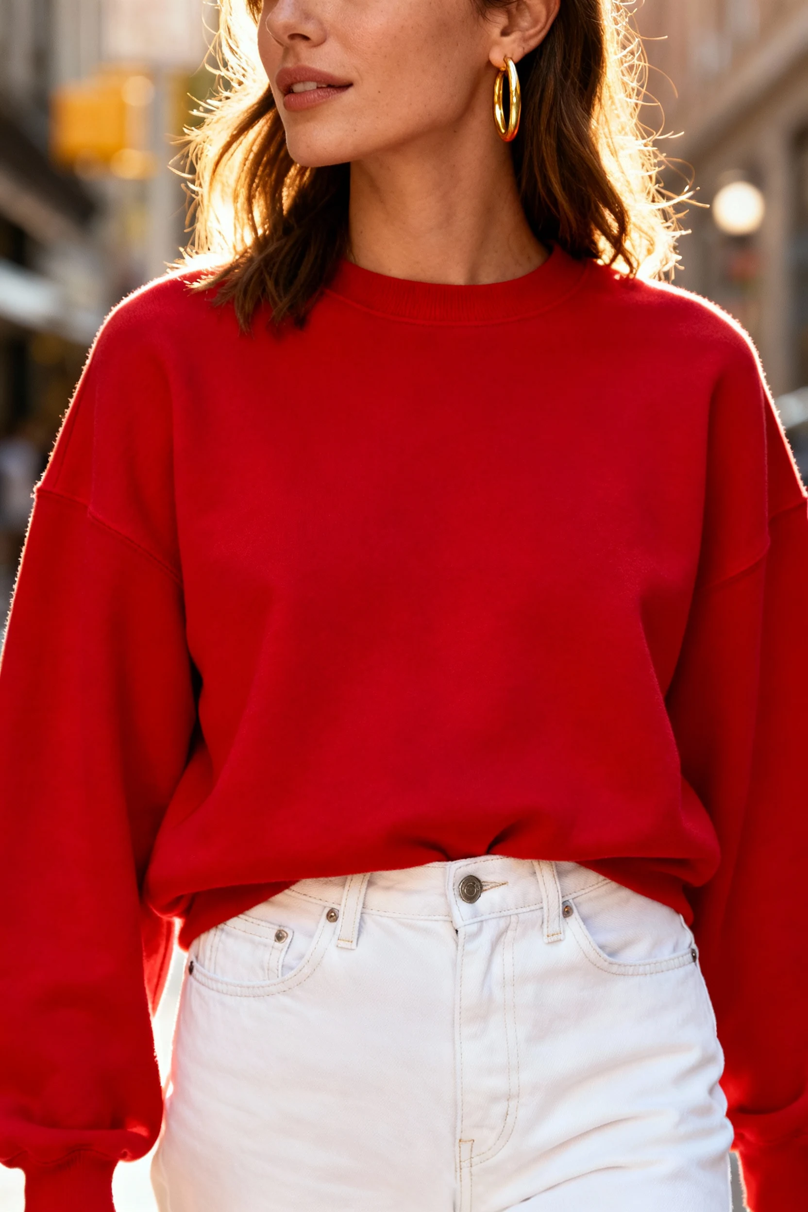 closeup female red crewneck sweater, white denim jeans, gold hoops