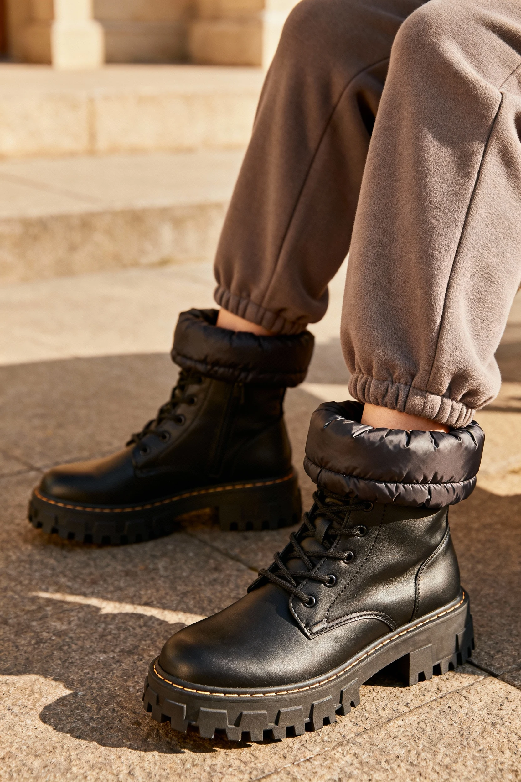 1. closeup female legs in lug-sole boots, joggers tucked, puffer hem