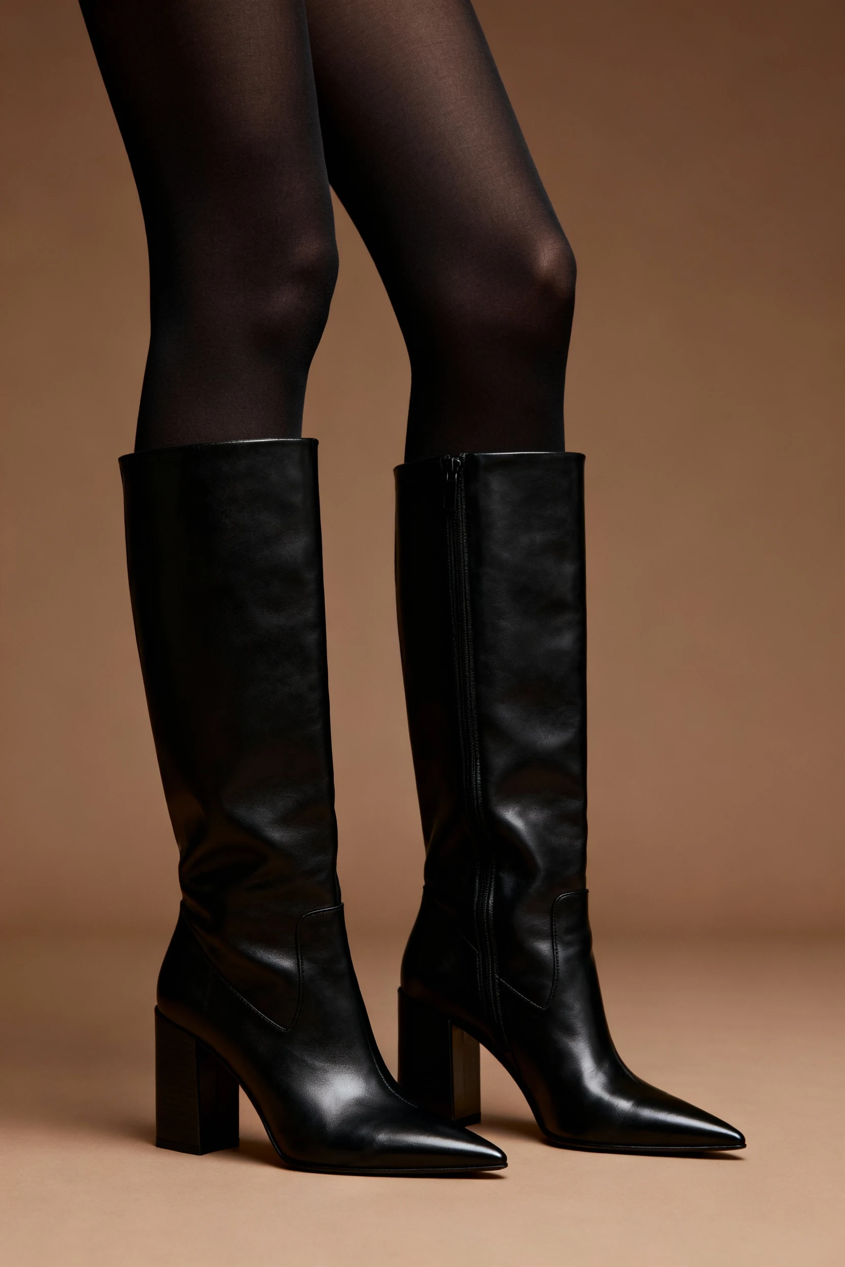 closeup female legs in black opaque tights, leather knee-high boots