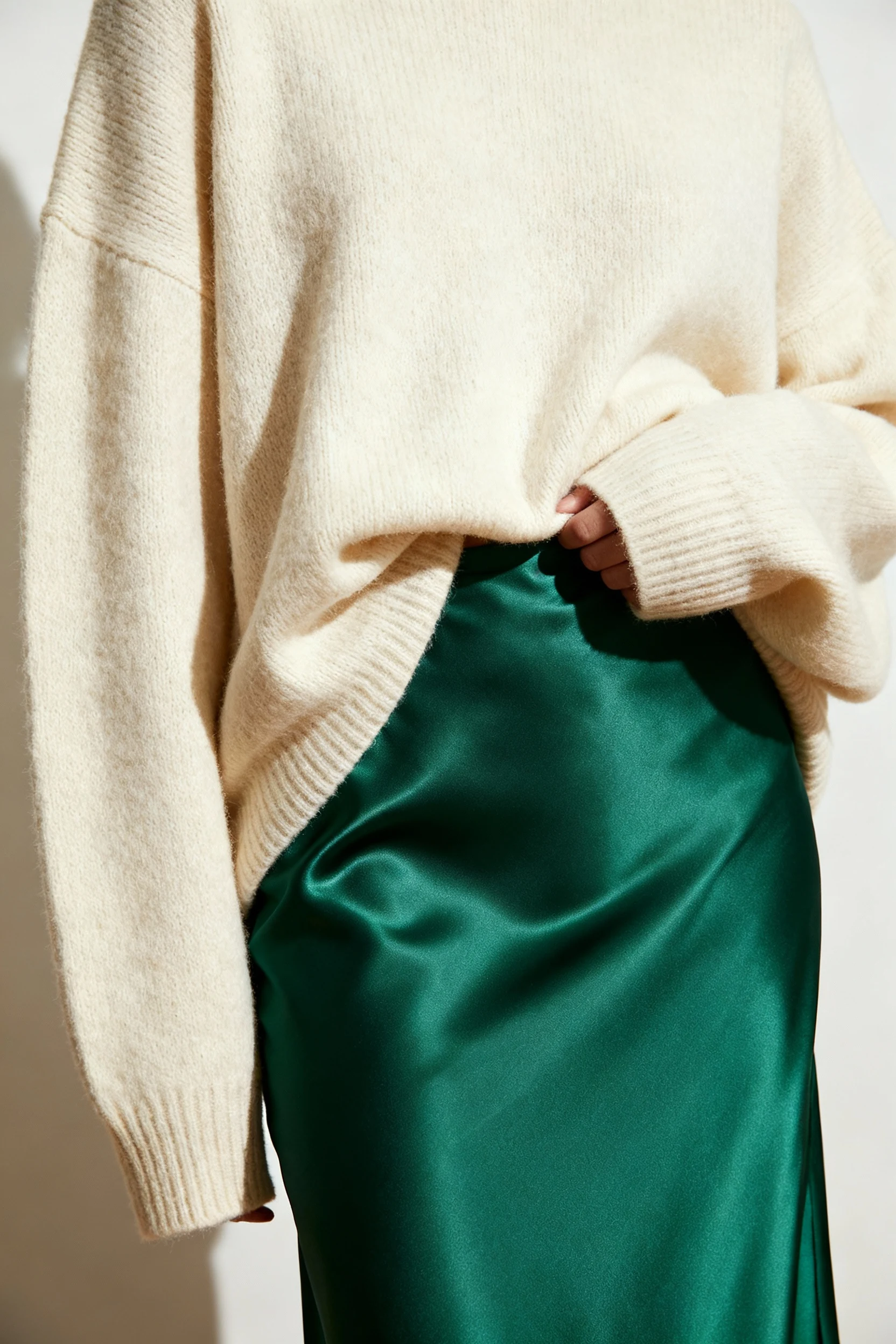 closeup cream oversized sweater front-tucked into emerald satin slip skirt