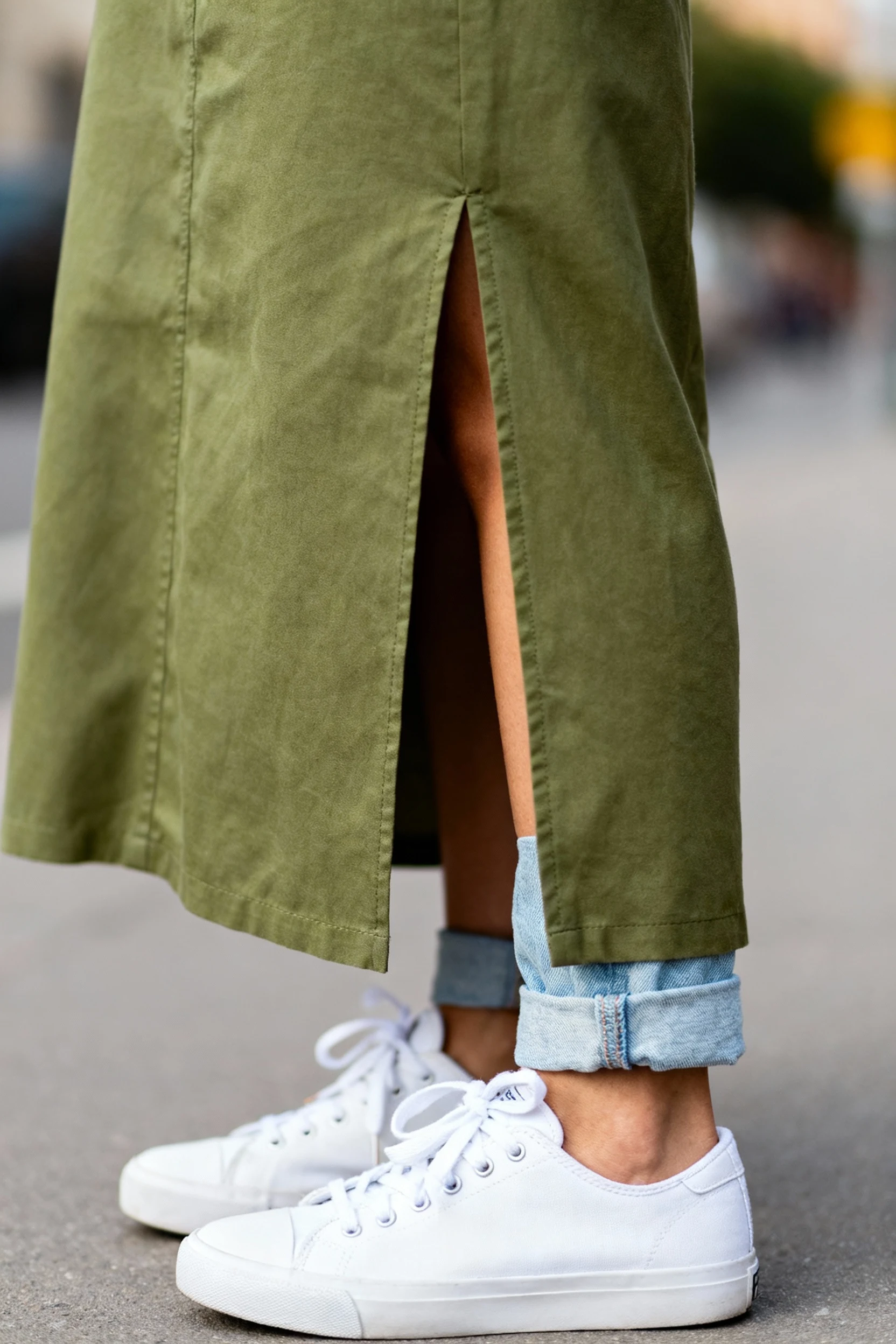 closeup female sage skirt slit, white sneakers, light denim cuff
