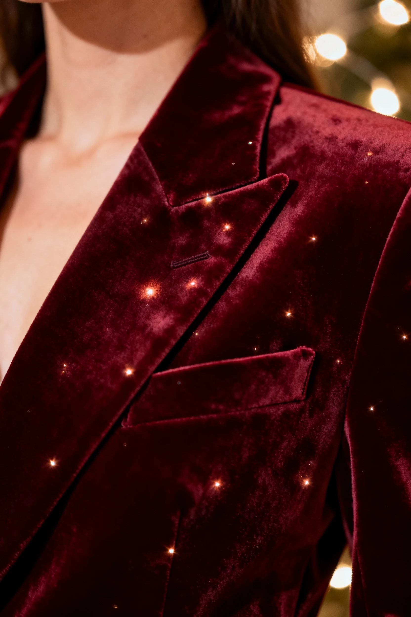 closeup female burgundy velvet tuxedo blazer lapel, twinkly lights