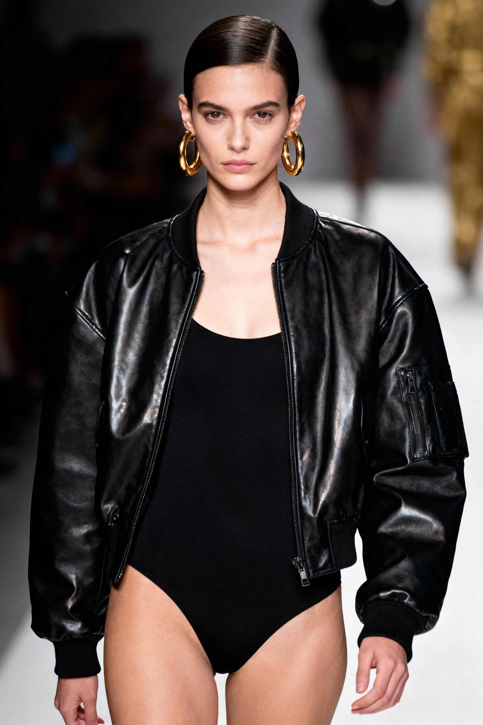 female closeup black bodysuit, oversized leather bomber, gold hoops