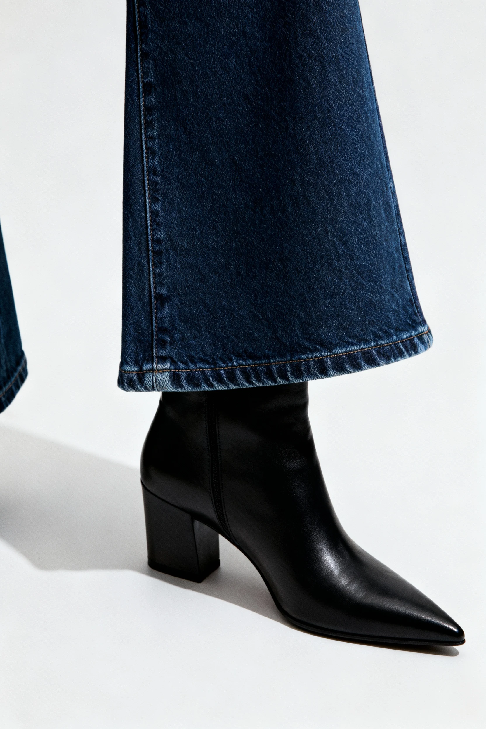 closeup dark indigo bootcut hem over black pointed ankle boots