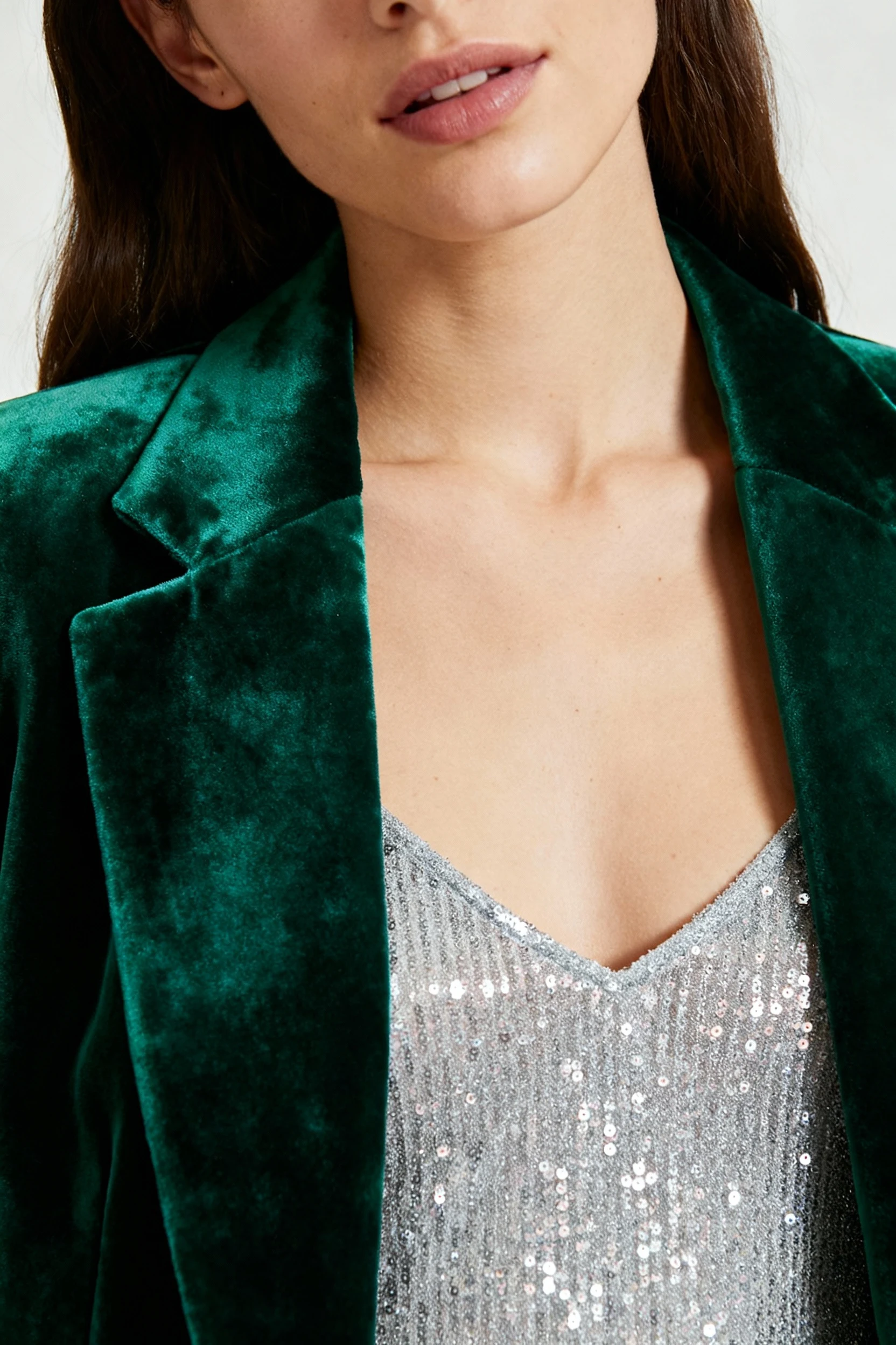 closeup female emerald velvet blazer over sparkly camisole