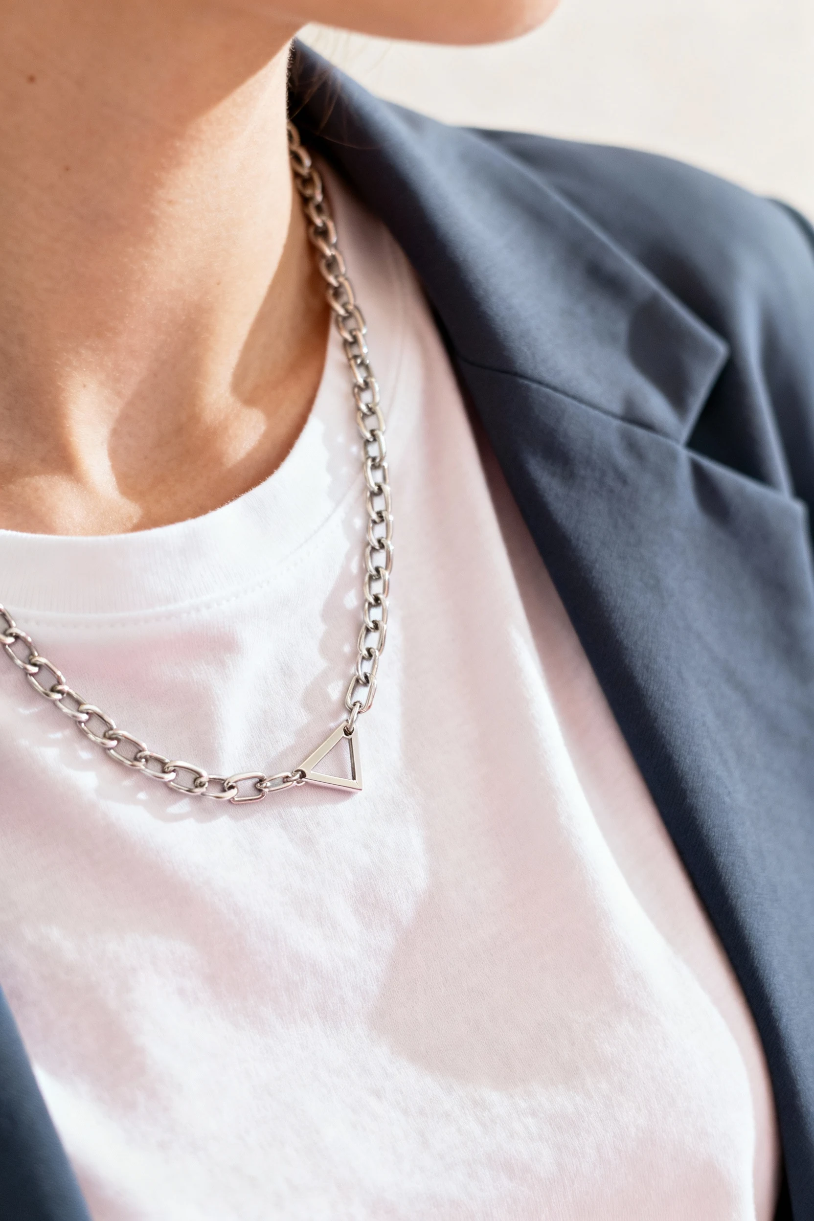 closeup female neck, delicate chain over crisp tee, blazer