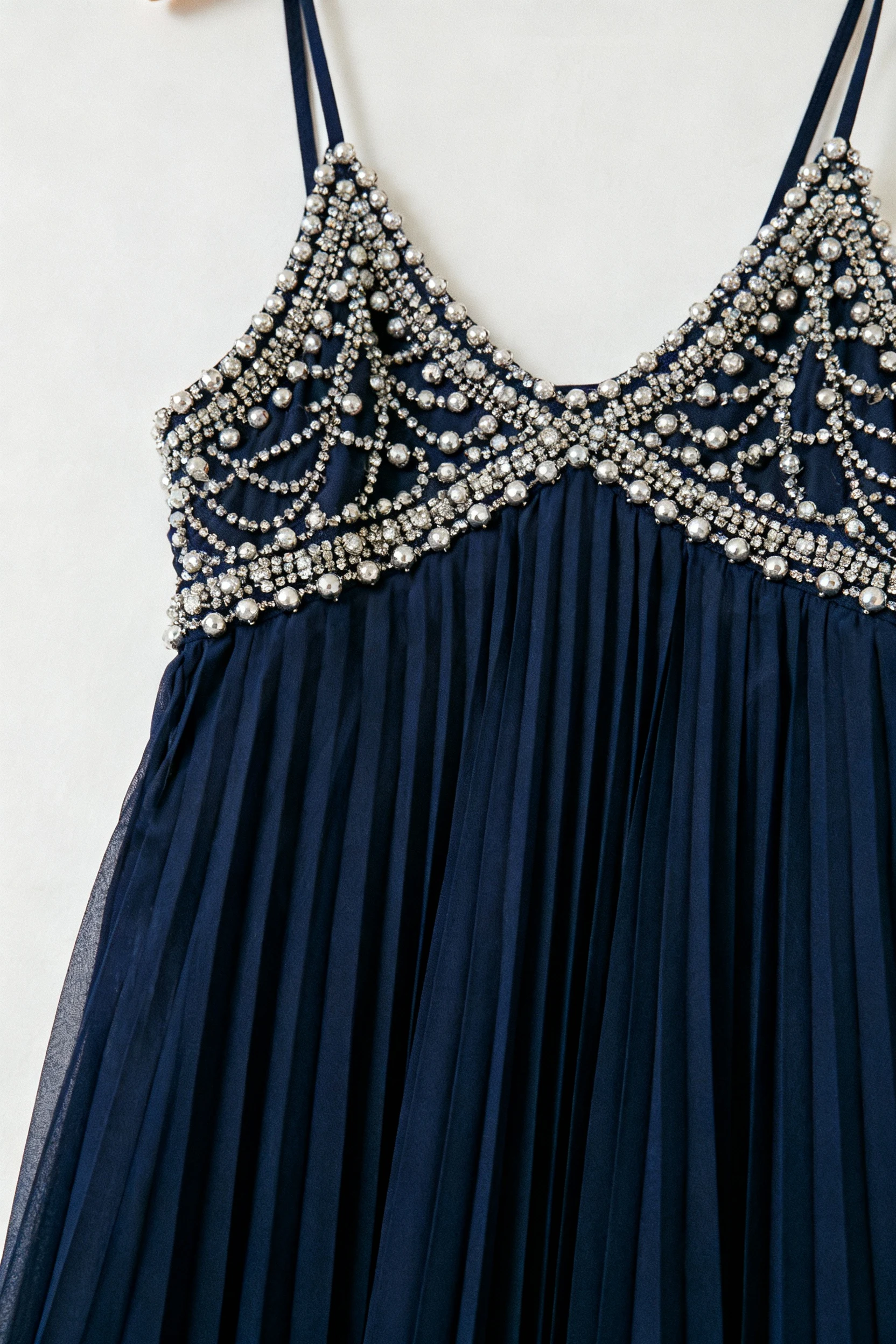 2. closeup beaded cami tucked into navy pleated chiffon midi