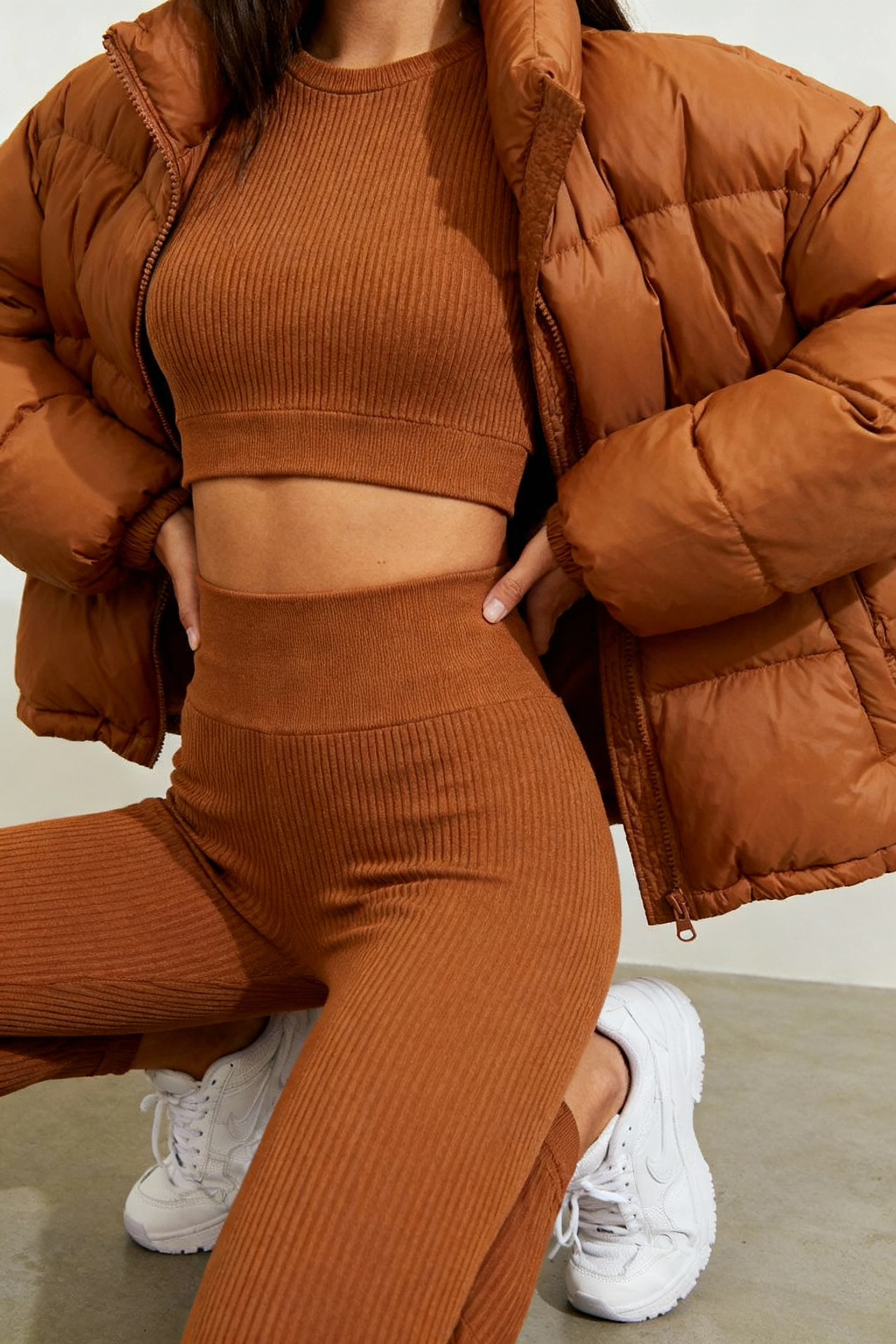 female closeup caramel cropped puffer, ribbed knit set, sneakers