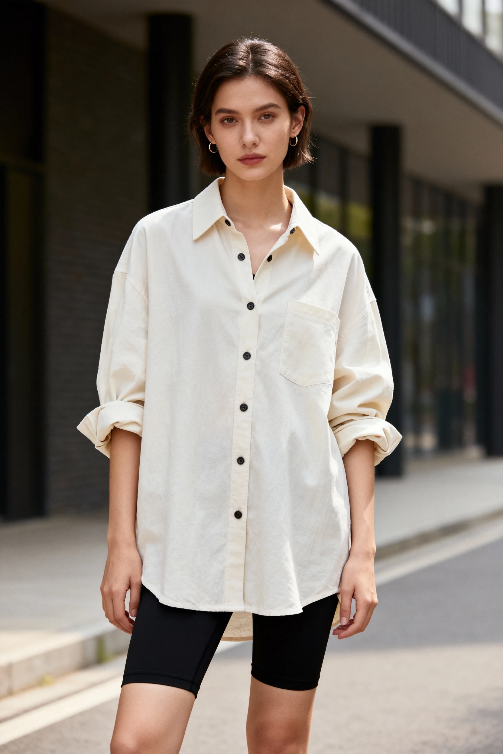 rolled sleeves of oversized button-down over black biker shorts