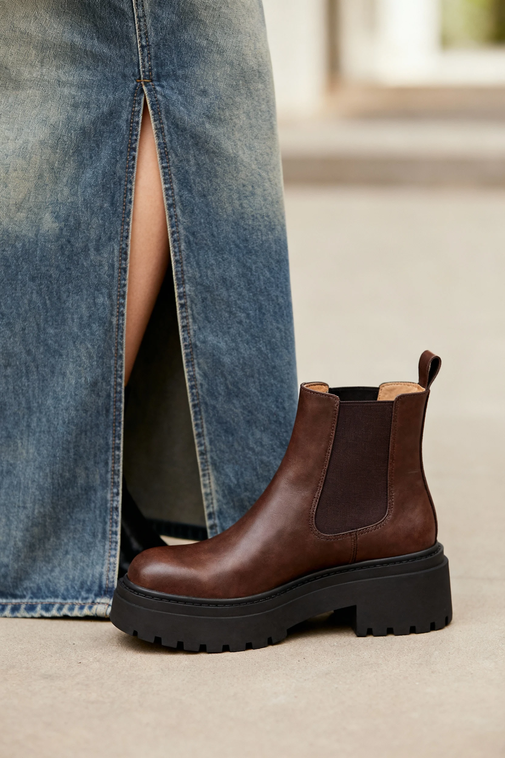 closeup chunky Chelsea boots beside maxi denim skirt front slit