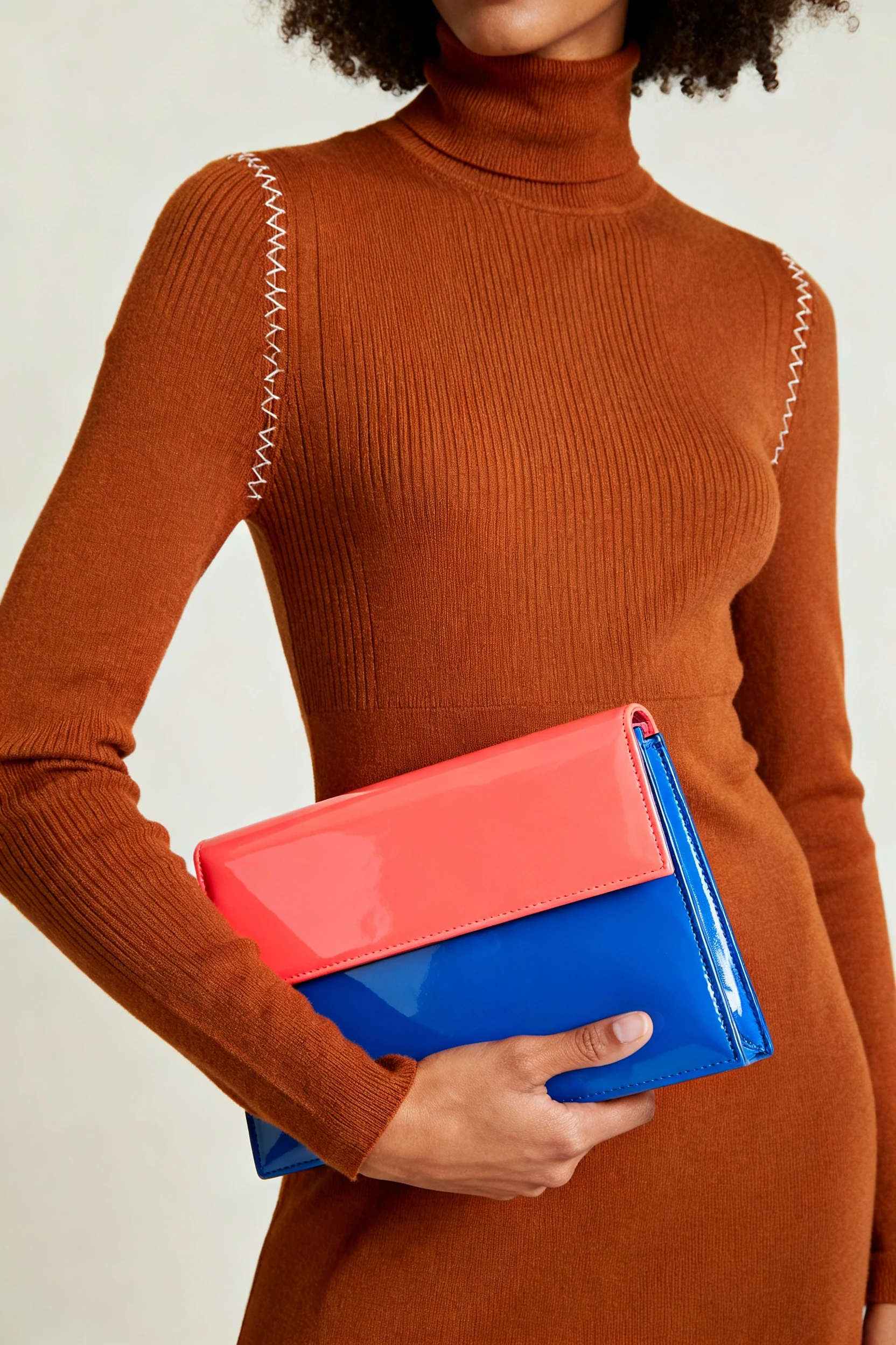closeup of caramel turtleneck dress with pop-of-color clutch