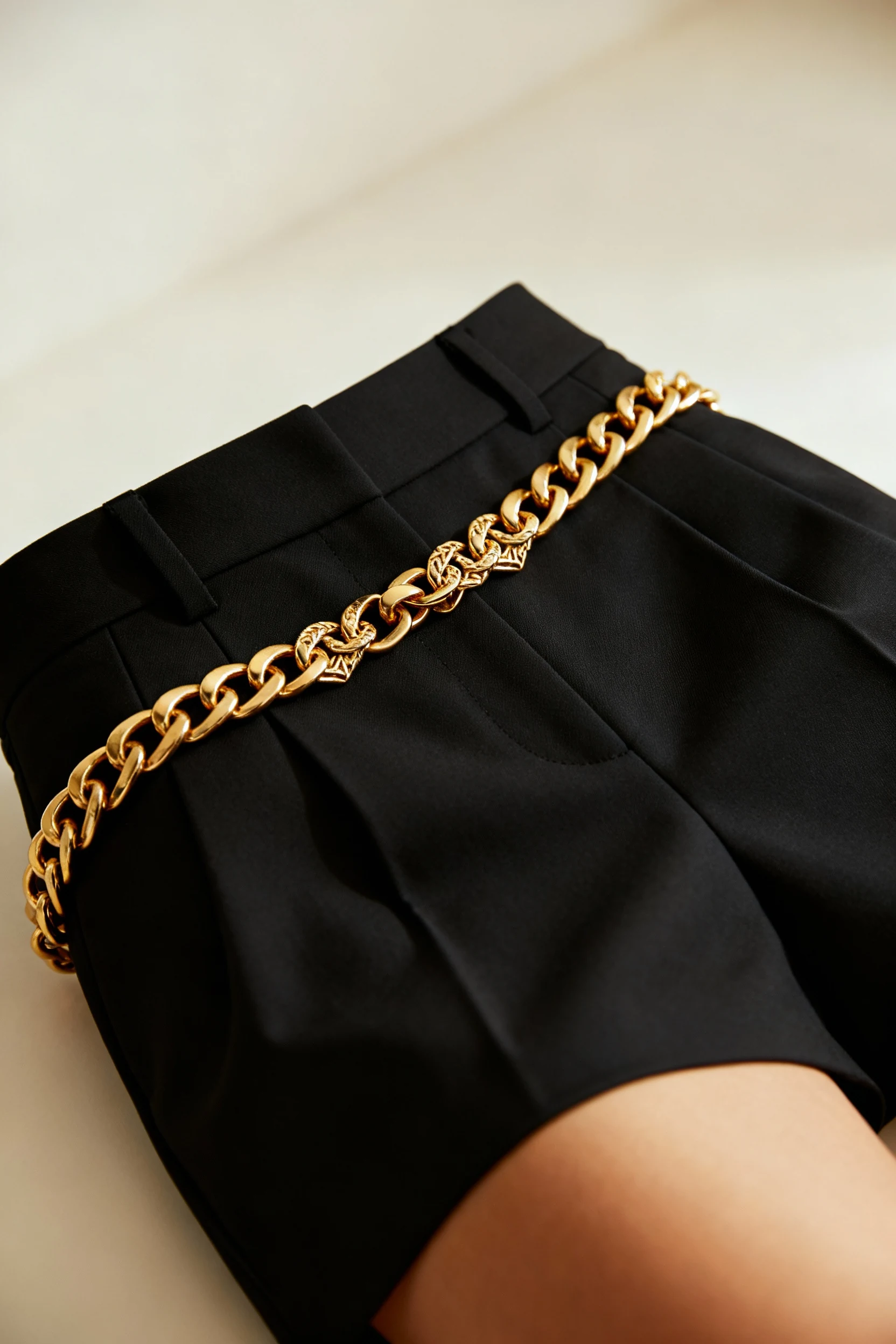closeup of gold waist chain on black tailored shorts