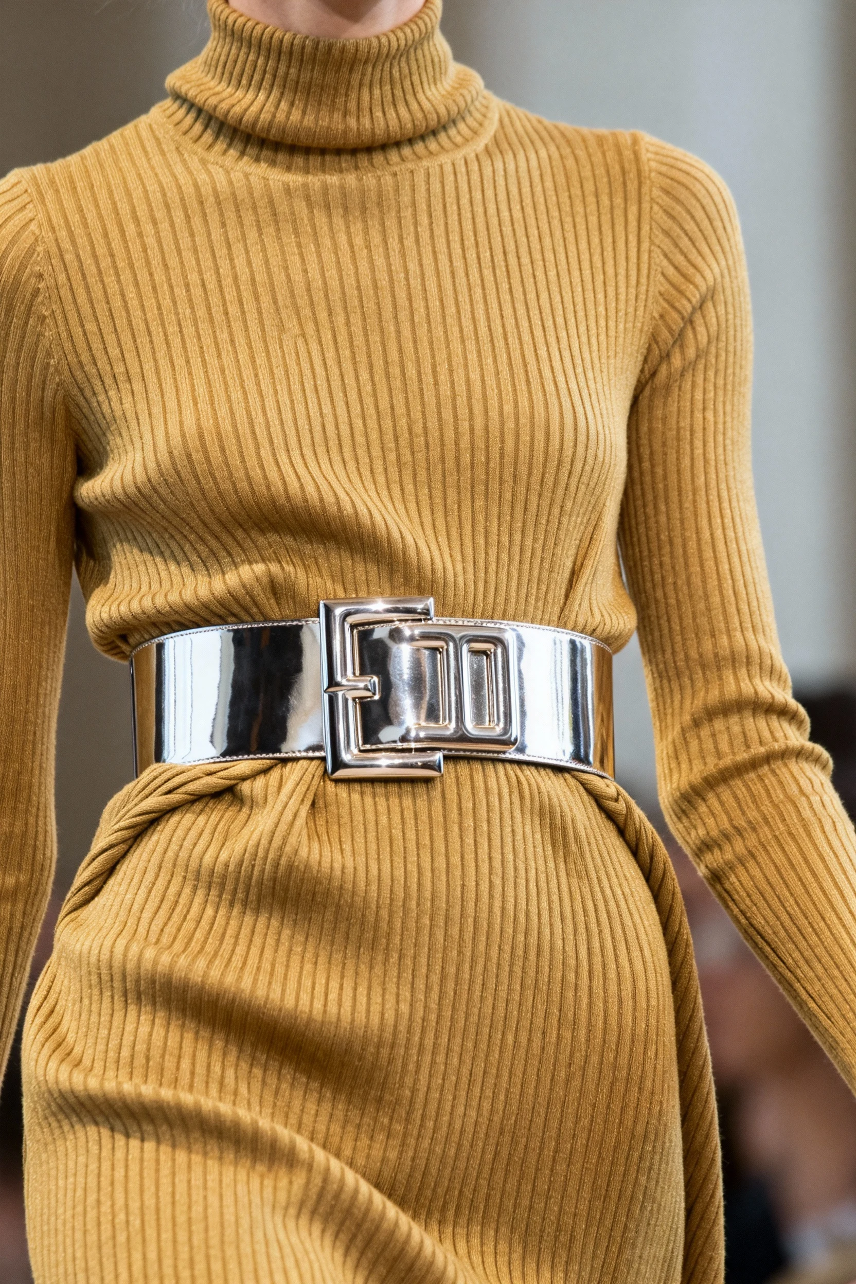 closeup of ribbed turtleneck dress cinched with wide metallic statement belt