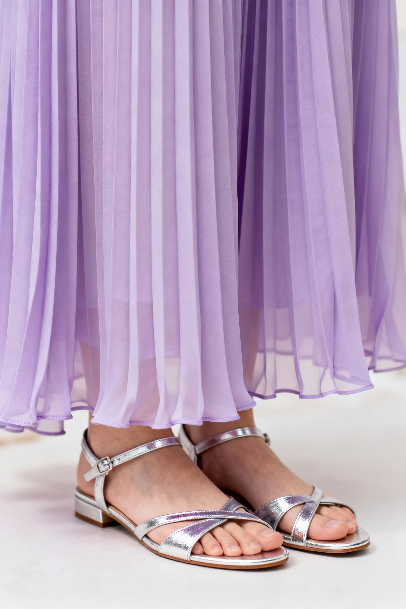 closeup silver strappy flats beneath lilac pleated maxi hem