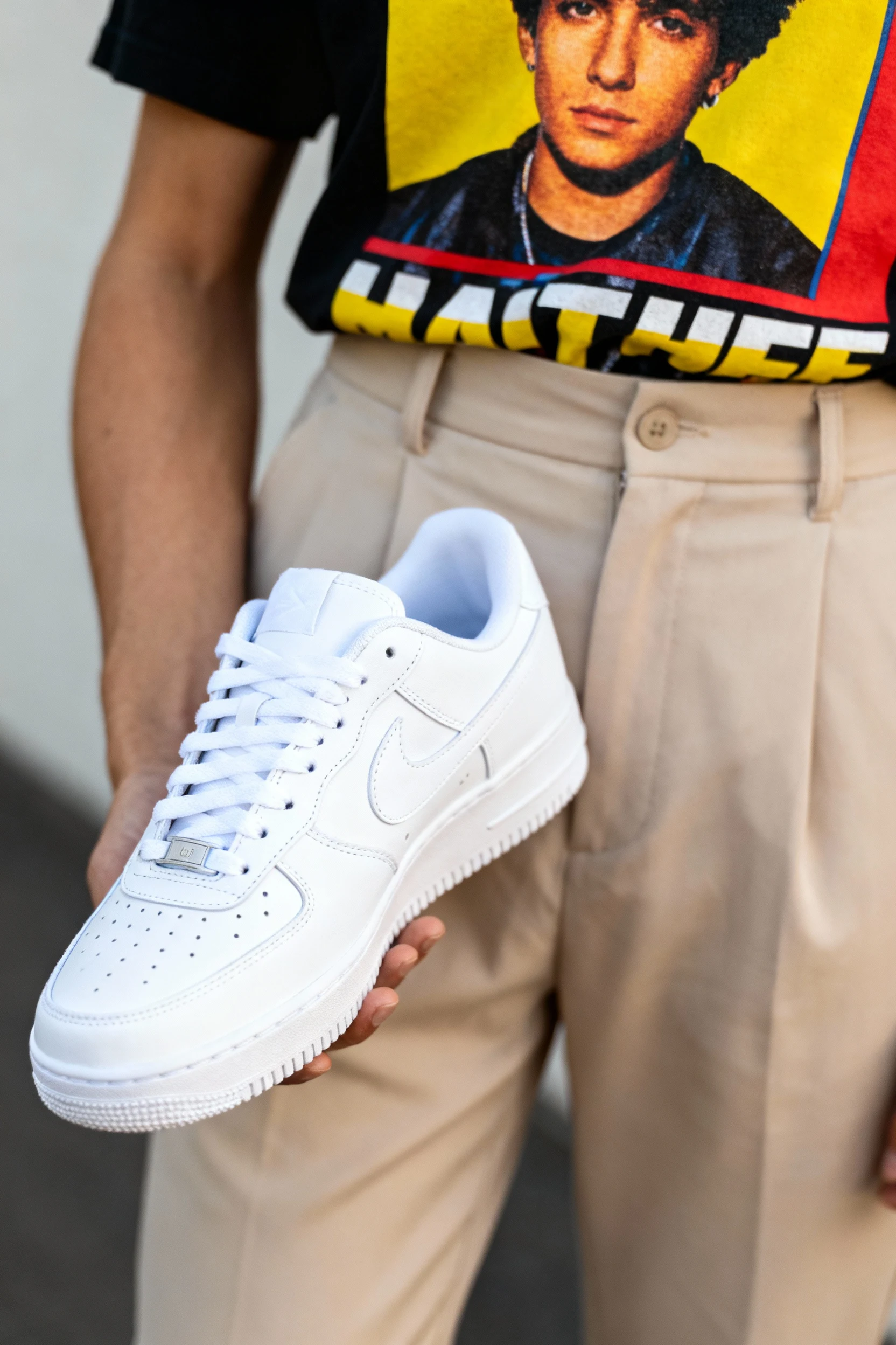 closeup of white sneakers with tucked-in graphic tee and high-waisted trousers